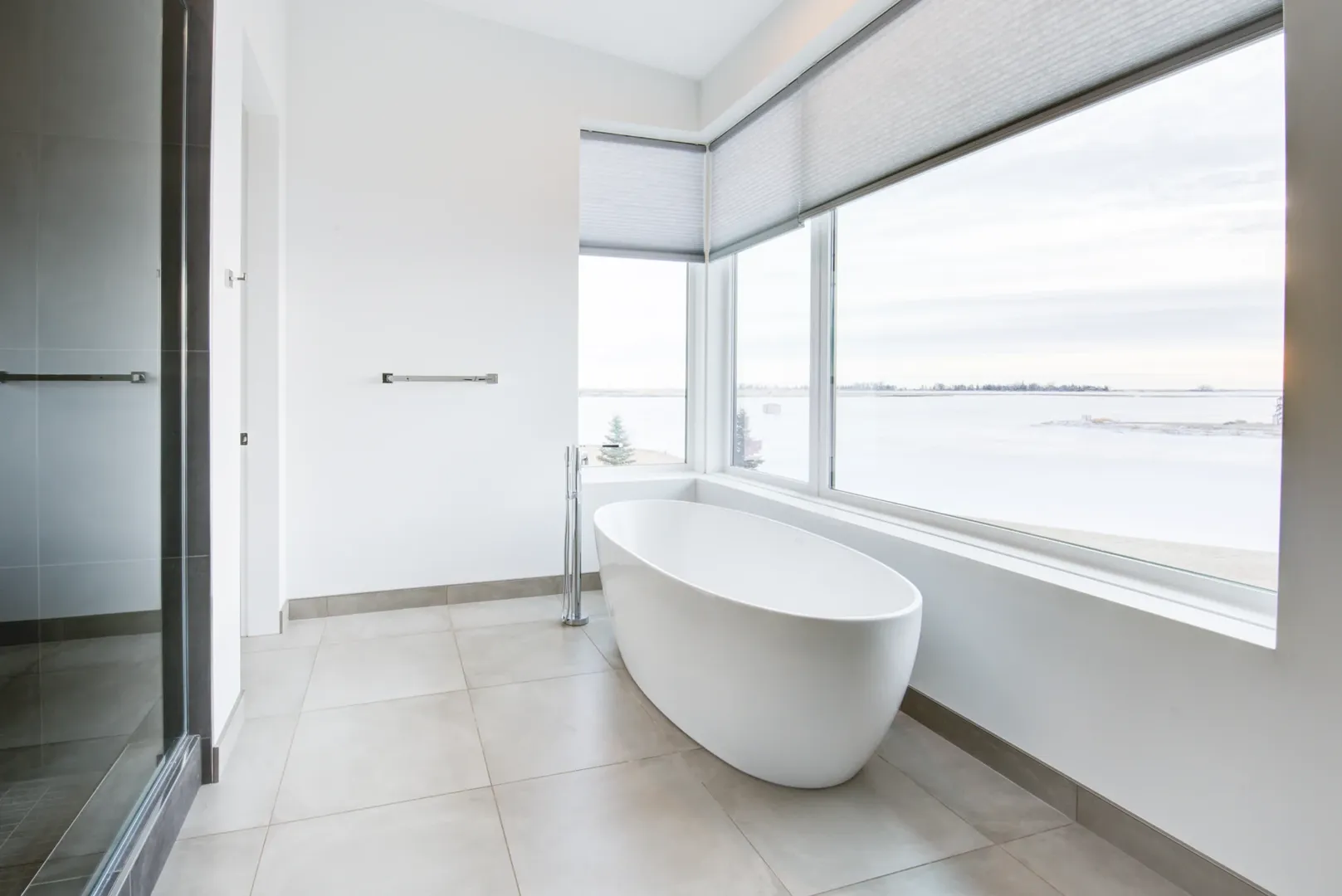 Freestanding bath beside expansive windows overlooking the prairie