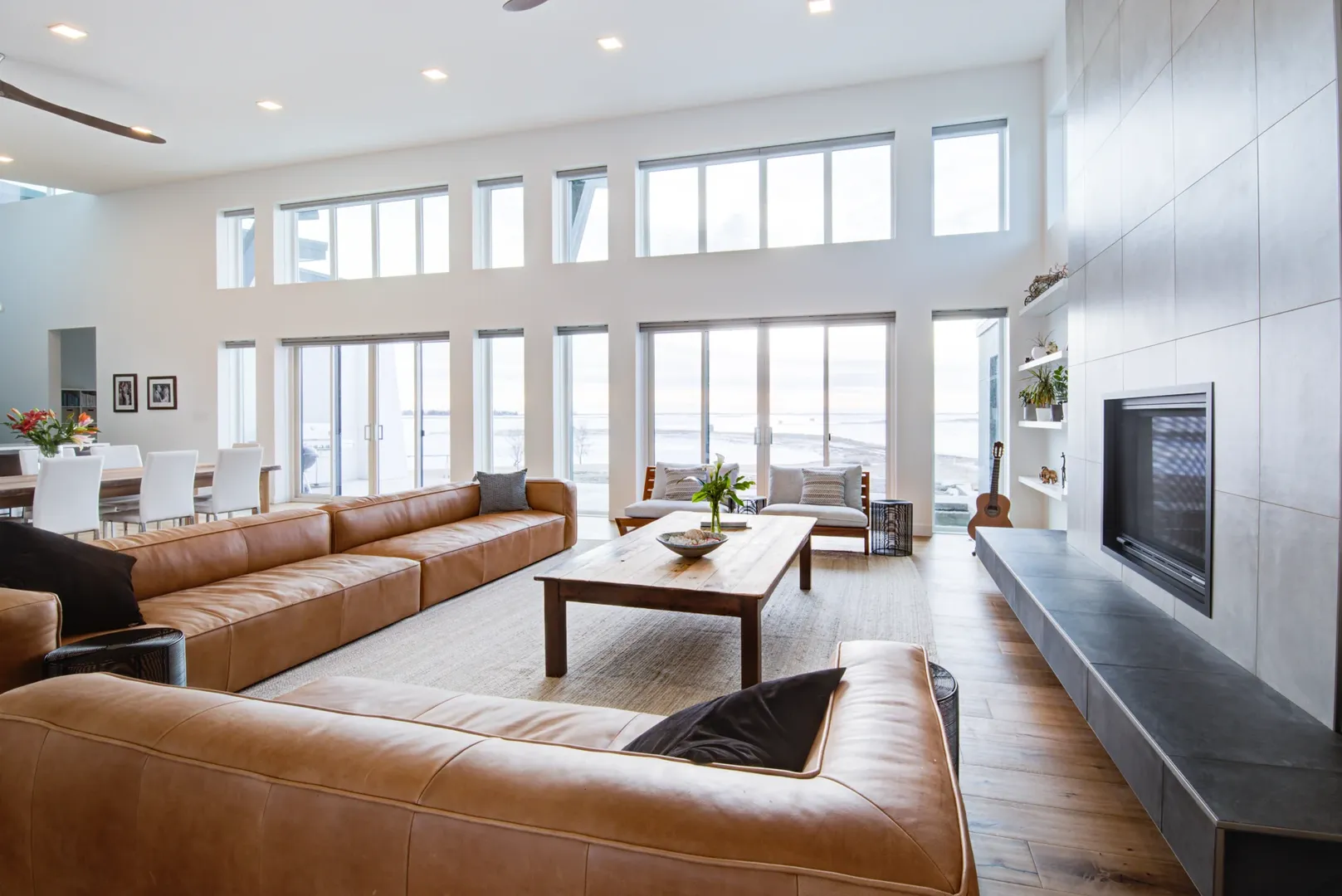 Light-filled Kenco living room with leather sofas, a stone fireplace and tall windows