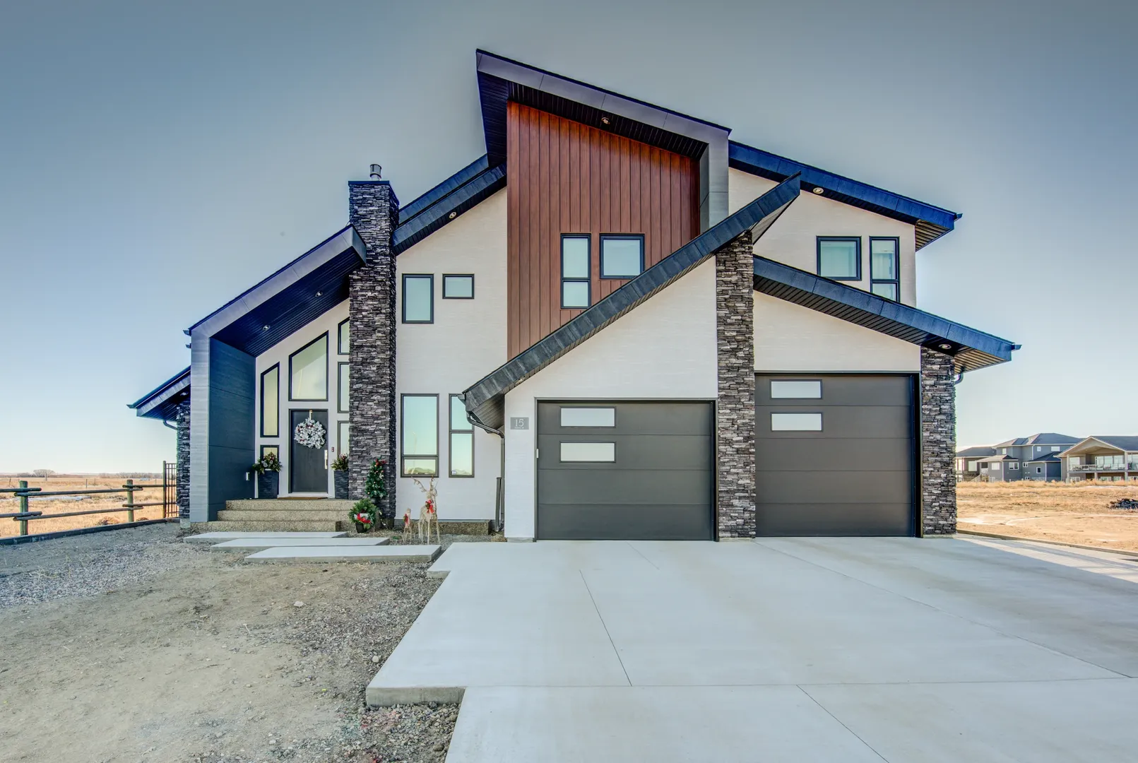 Kenco custom home with angular rooflines, stone columns and warm timber siding